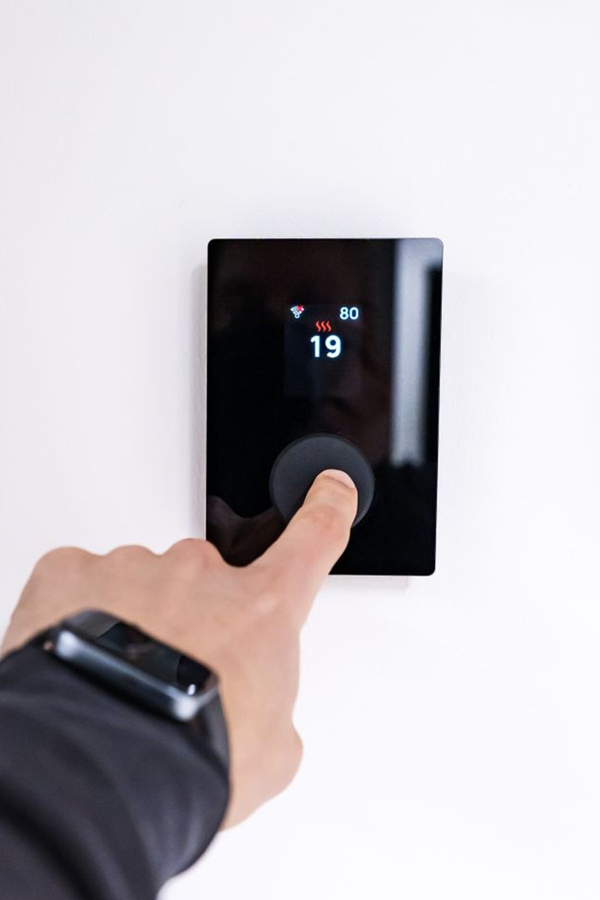 Hand adjusting a smart thermostat on the wall