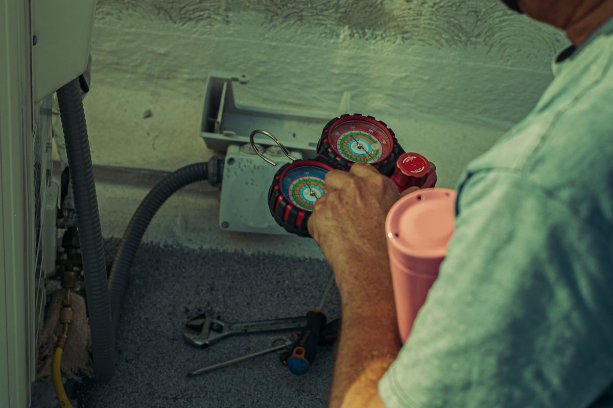 HVAC technician checking an air conditioner with refrigerant manifold gauges and tools