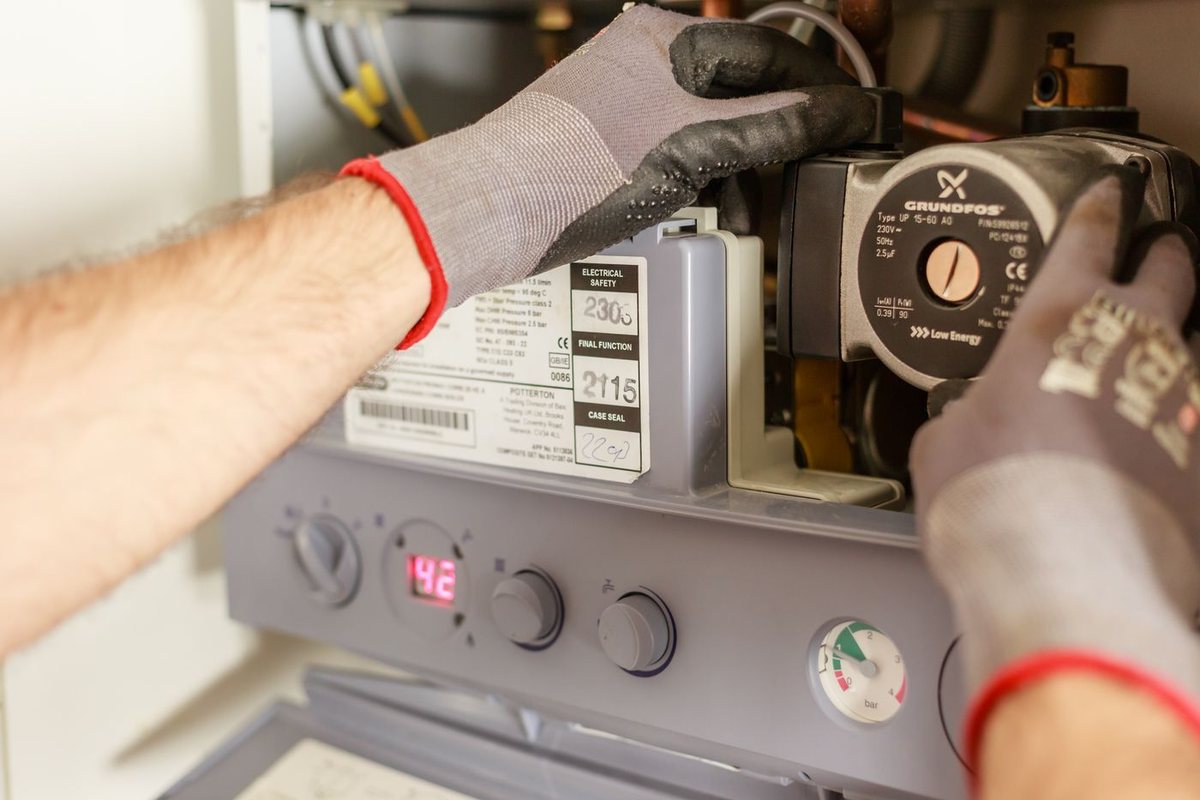 Technician servicing a gas furnace control panel