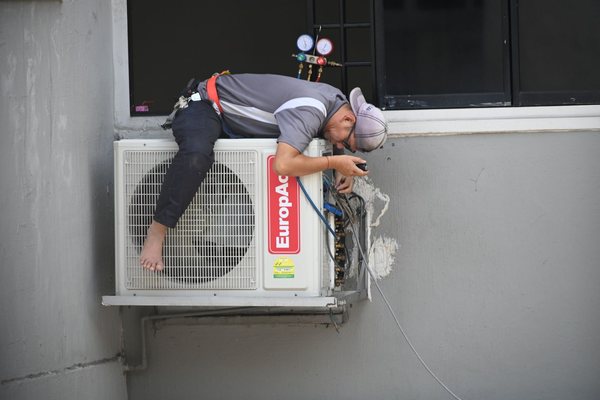 Technician servicing a wall-mounted condenser